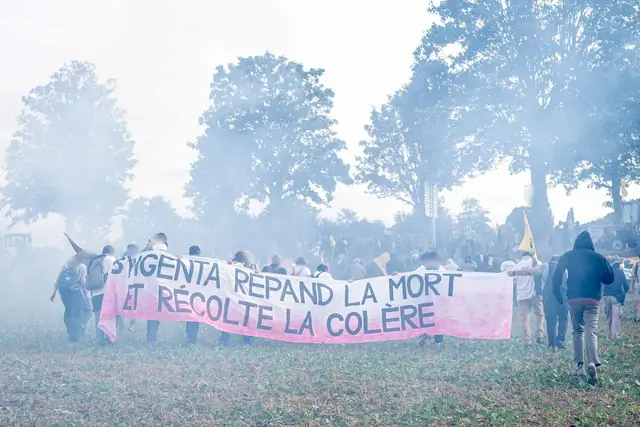La pancarta «Syngenta siembra la muerte y cosecha la rabia» («Syngenta répand la mort et récolte la colère») en una nube de gas lacrimógeno