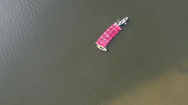 Vista aérea de kayaks que arrastran una pancarta rosa flotante por el Sena