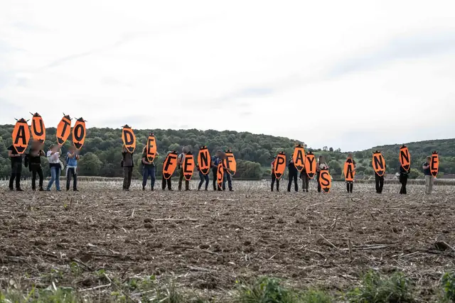 En un campo arado, unas letras naranjas forman «Autodefensa campesina» («Autodéfense paysanne»)