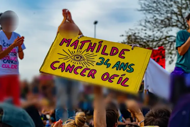 Un cartel amarillo, «Mathilde, 34 años, cáncer de ojo» («Mathilde, 34 ans, cancer de l’œil»), alzado por encima de la multitud
