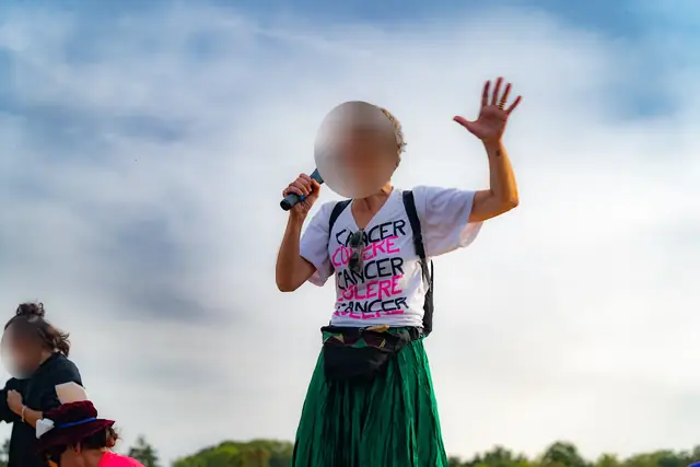 مناضلة من Cancer Colère تأخذ الكلمة عبر الميكروفون، واقفة على منصة جرار