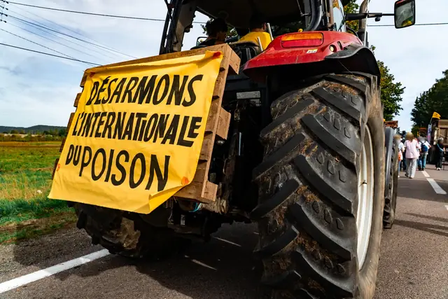 Un tractor luce la pancarta «Desarmemos la internacional del veneno» («Désarmons l’internationale du poison»)